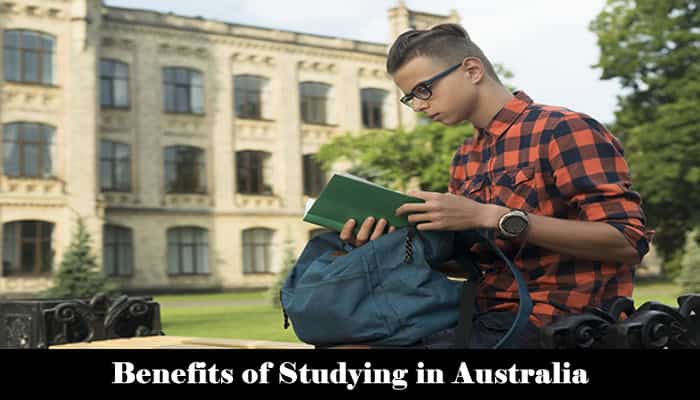 Smiling international student with backpack and documents, standing in front of an Australian university campus